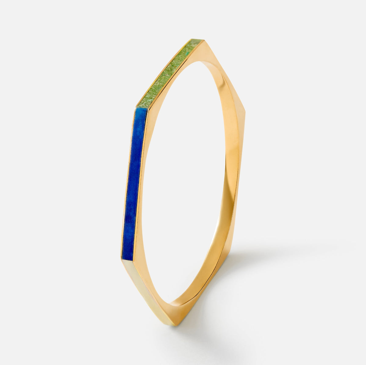 A gold-toned geometric bangle bracelet with a vibrant blue inlay and a textured green inlay, shown on a clean white background.