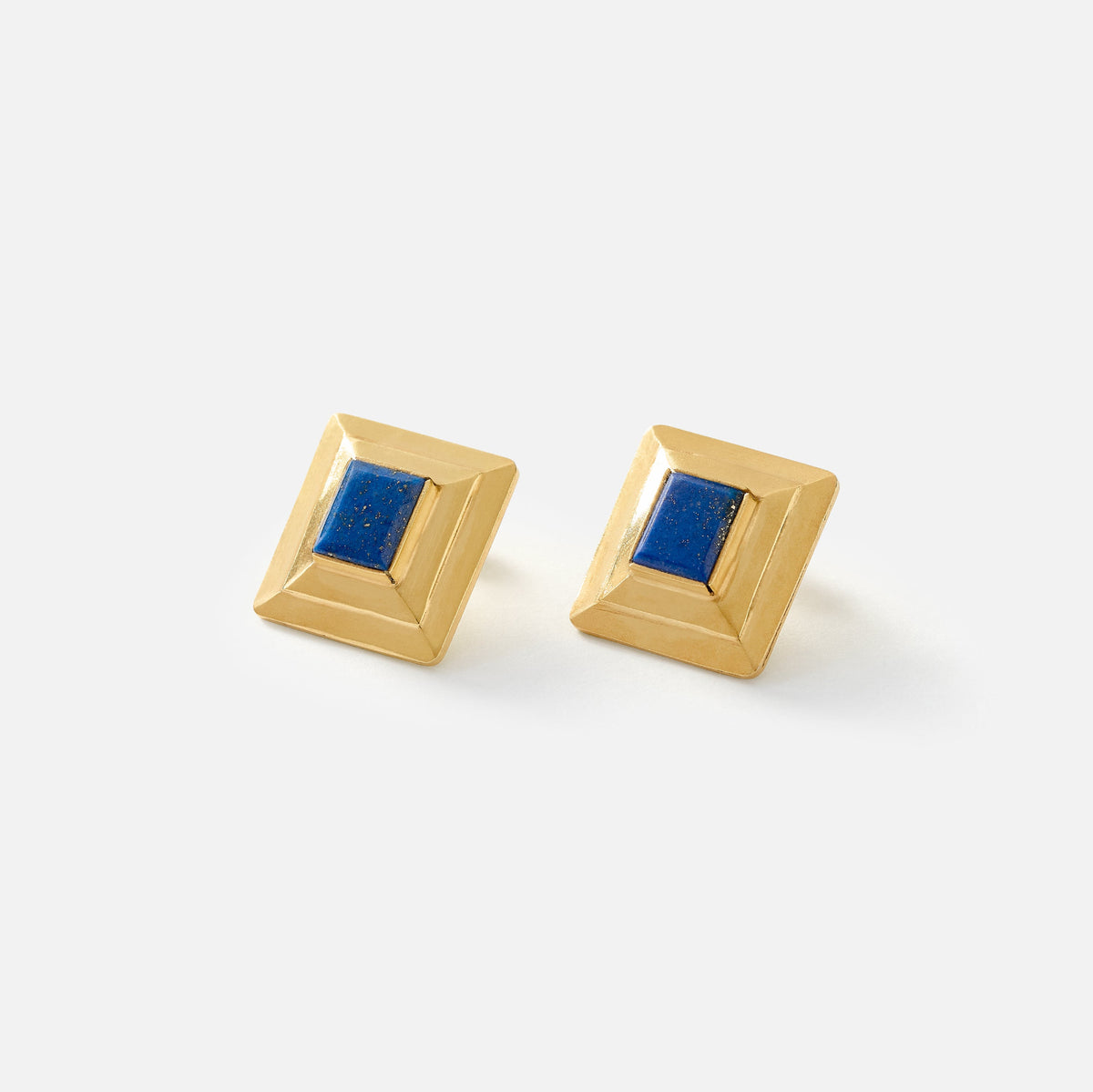 A pair of gold geometric stud earrings with a square blue lapis lazuli-style center, displayed on a clean white background.