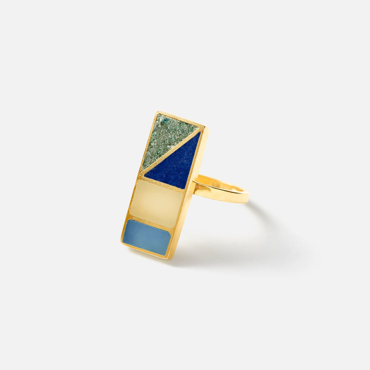 A gold geometric ring featuring a multi-colored rectangular face with segments of textured green, deep blue, light blue, and gold.