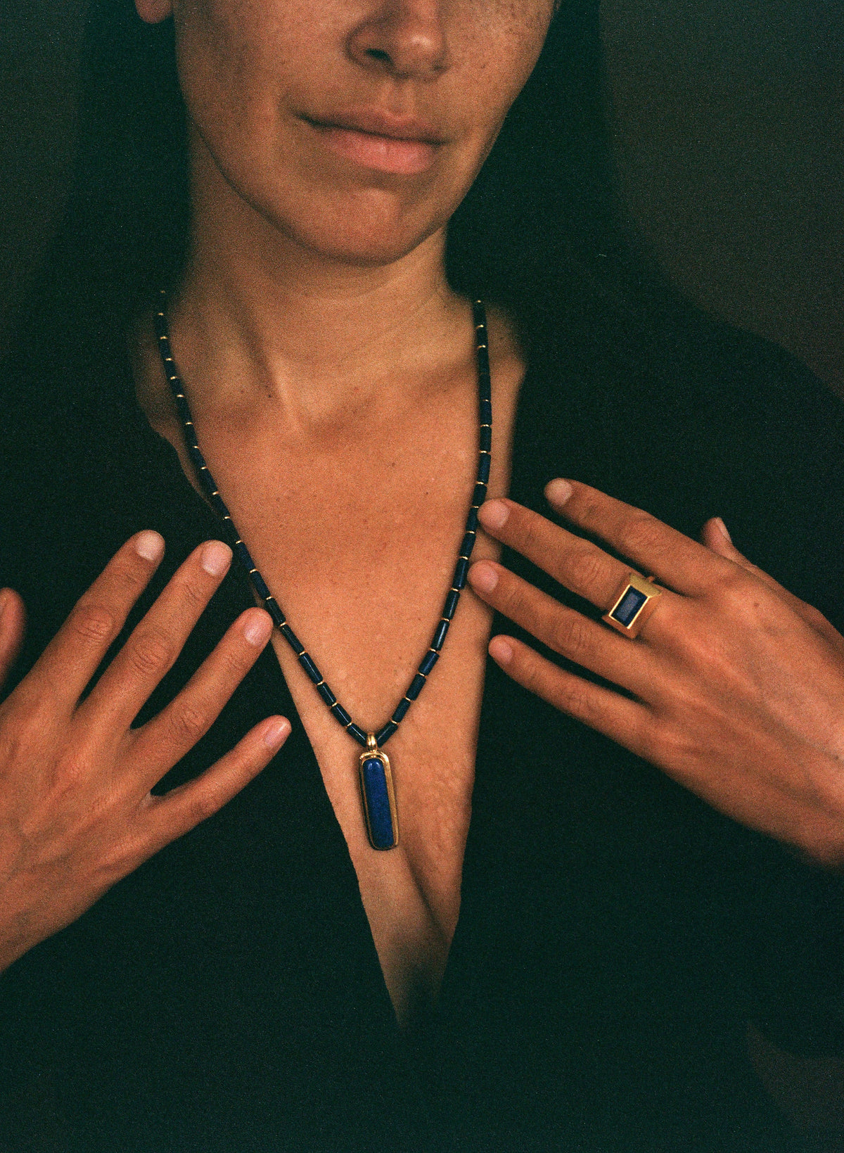 womane wearing a long lapis beaded necklace on 35mm film. Dark background