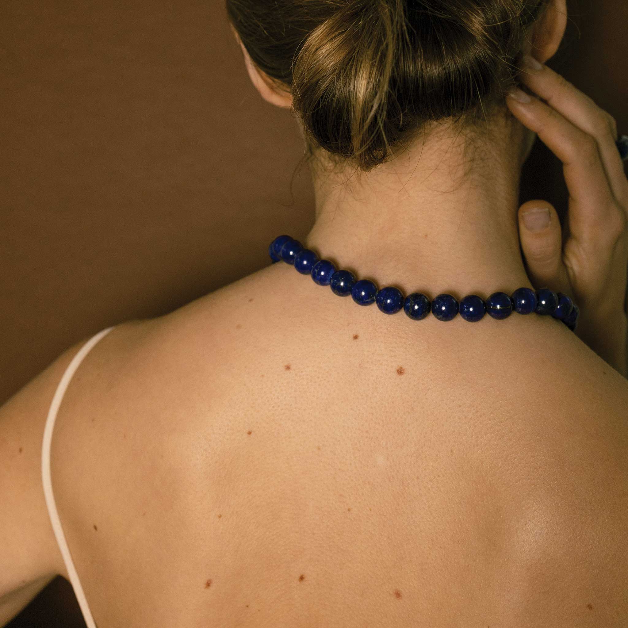 Lifestyle shot of the back of ISHKAR's lapis bead necklace.