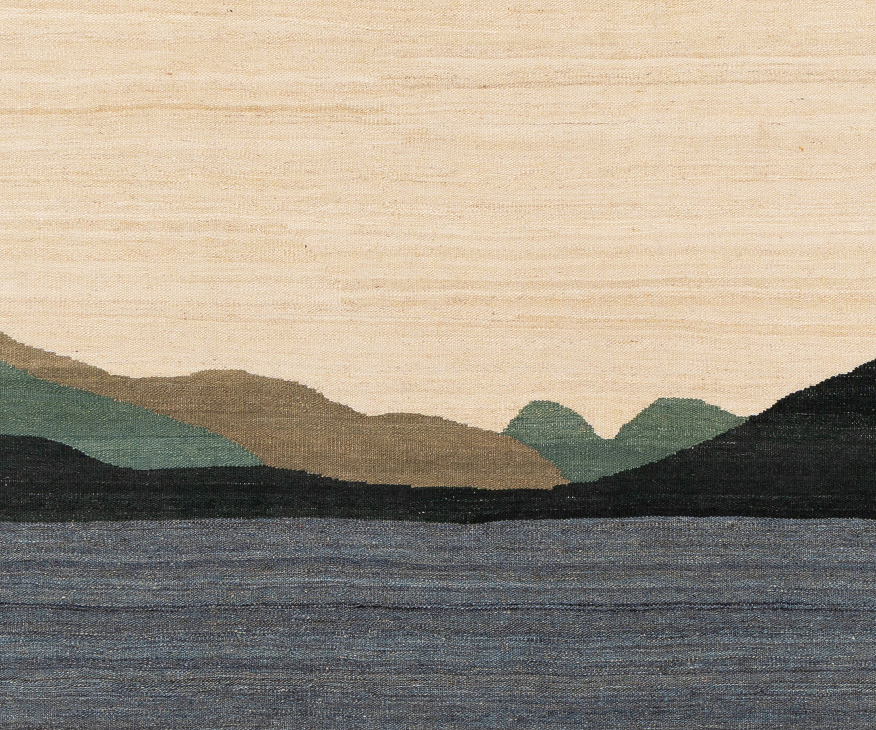 A close-up of an Afghan flatweave rug showing a stylized landscape with layered hills in beige, green, and dark charcoal, above a blue-gray lake.