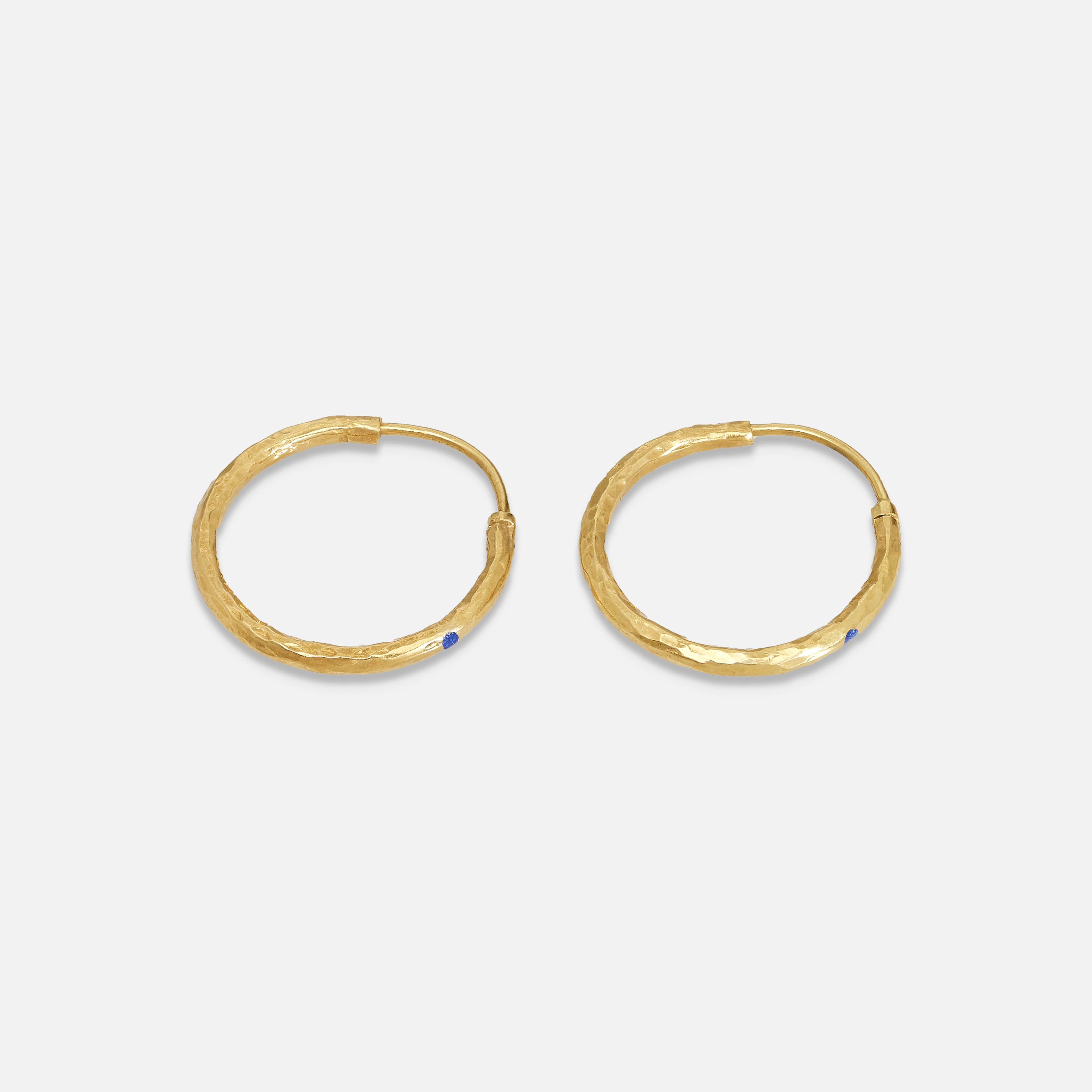 A pair of gold-colored hoop earrings with lapis accents on a white background.