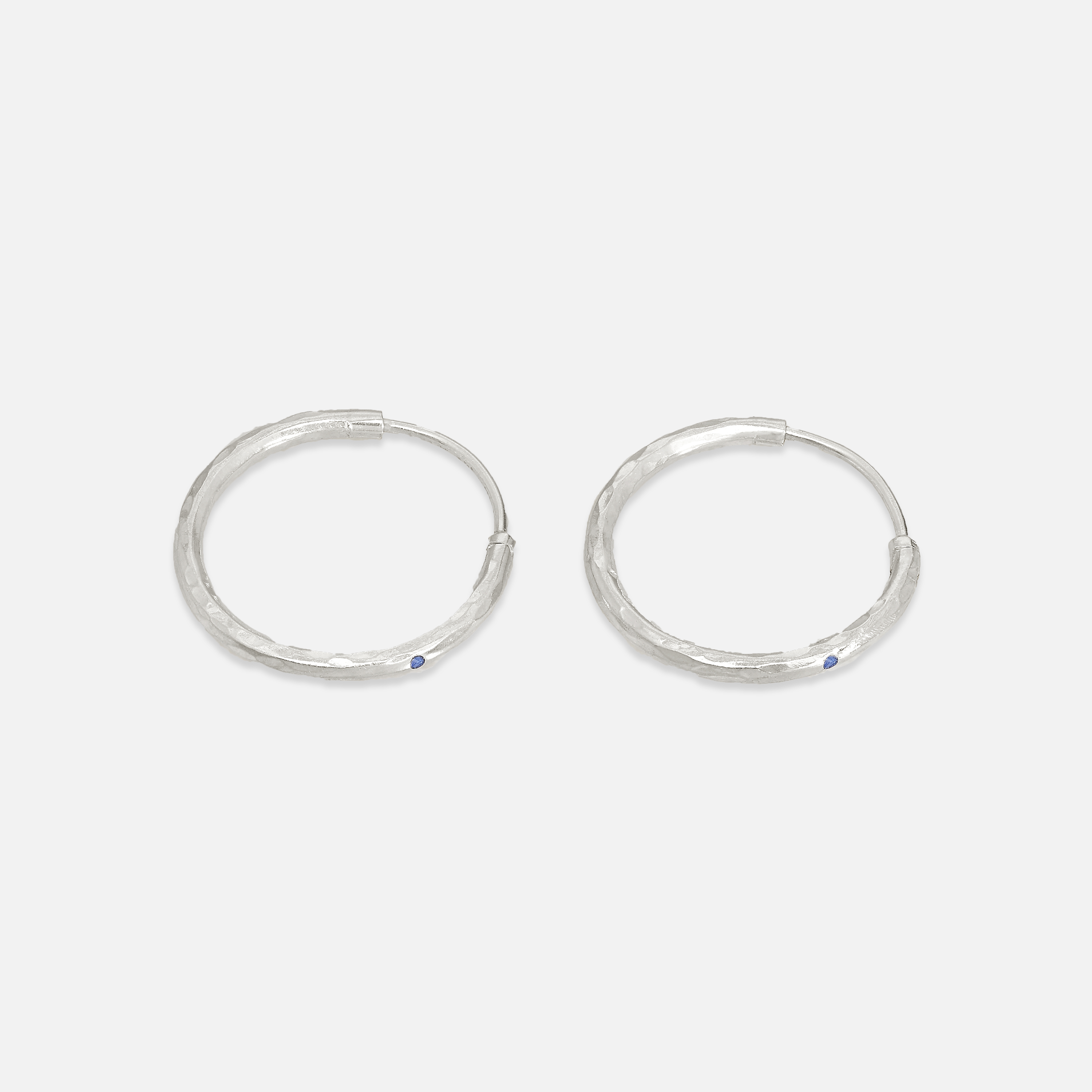 A pair of silver hoop earrings with lapis accents on a white background.