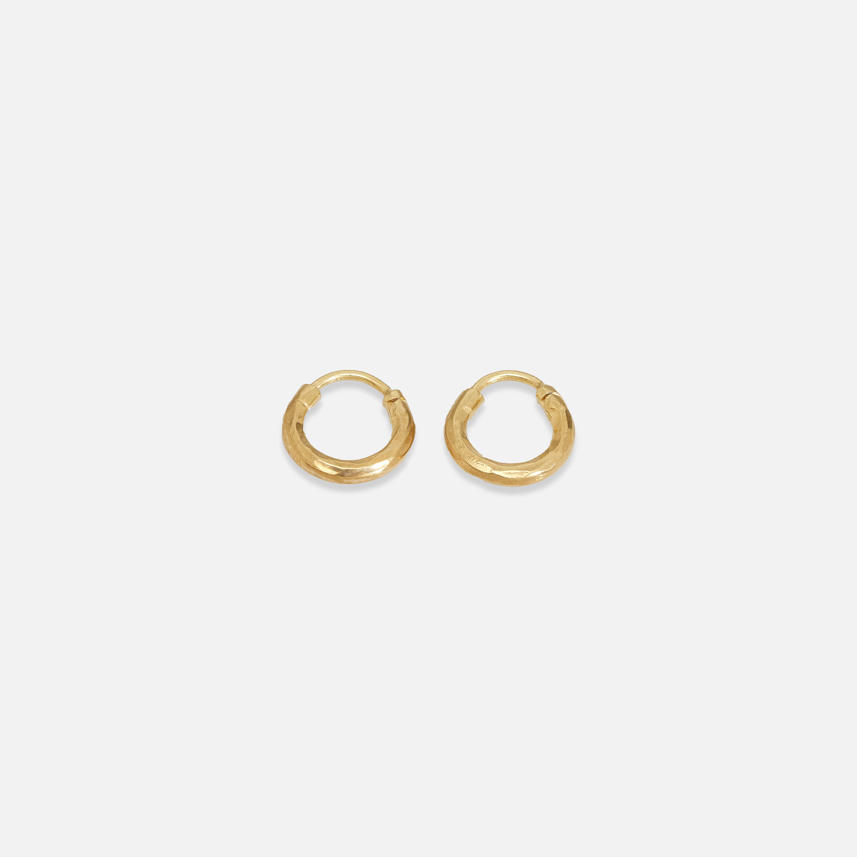 A pair of small gold-colored hoop earrings on a white background