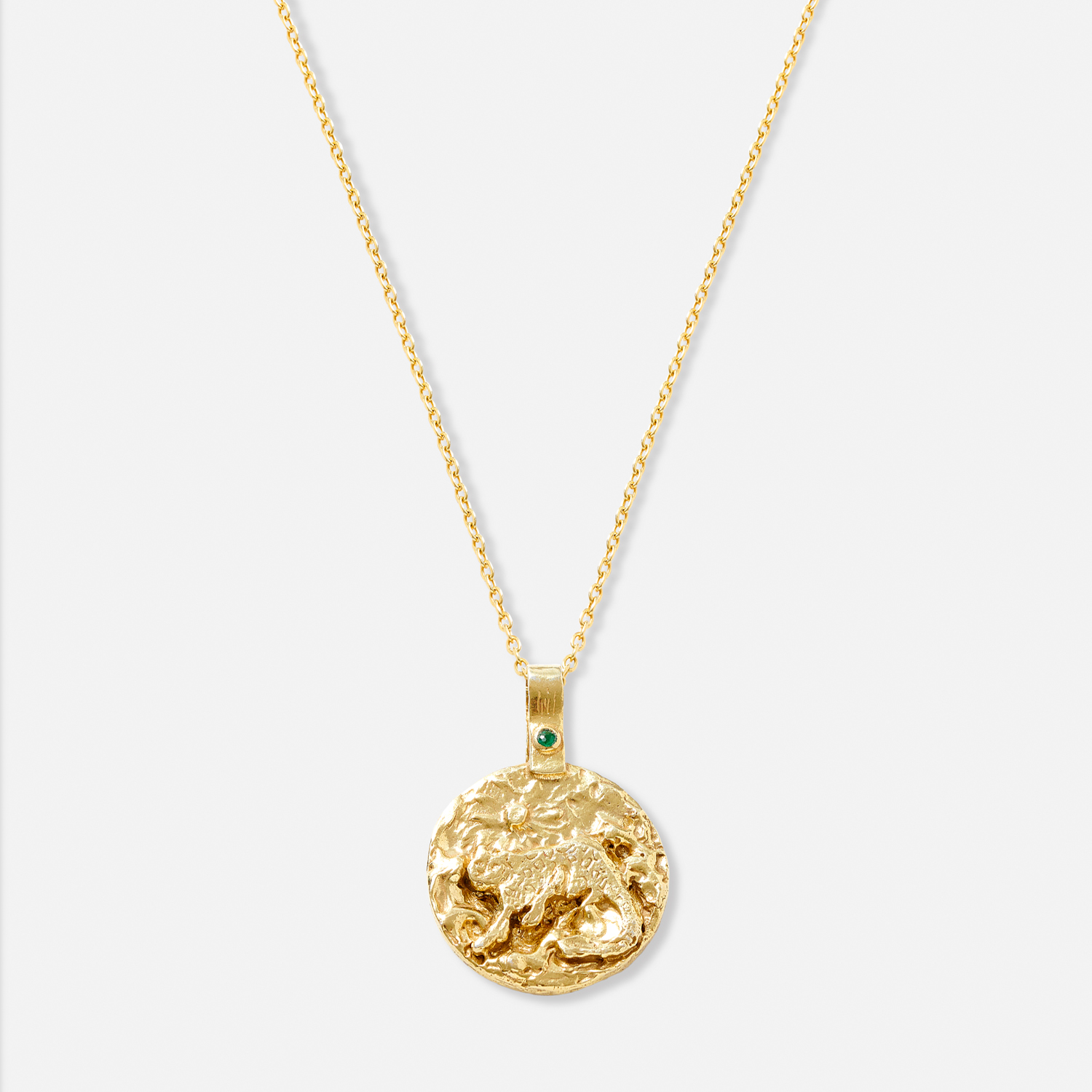 A gold-plated necklace with a circular pendant featuring a snow leopard and an emerald.