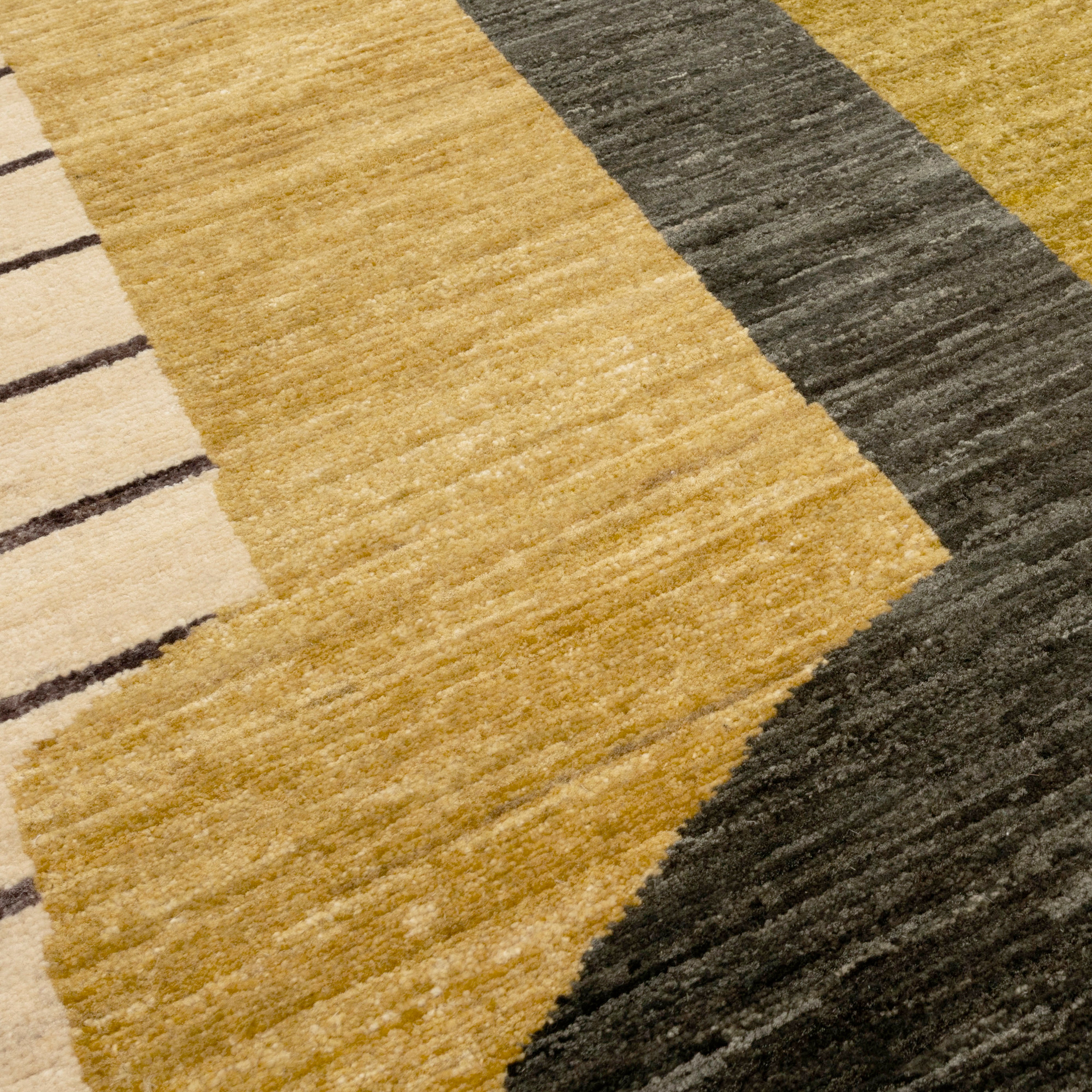 Close-up of a textured rug with geometric pattern in gold, green, and beige.