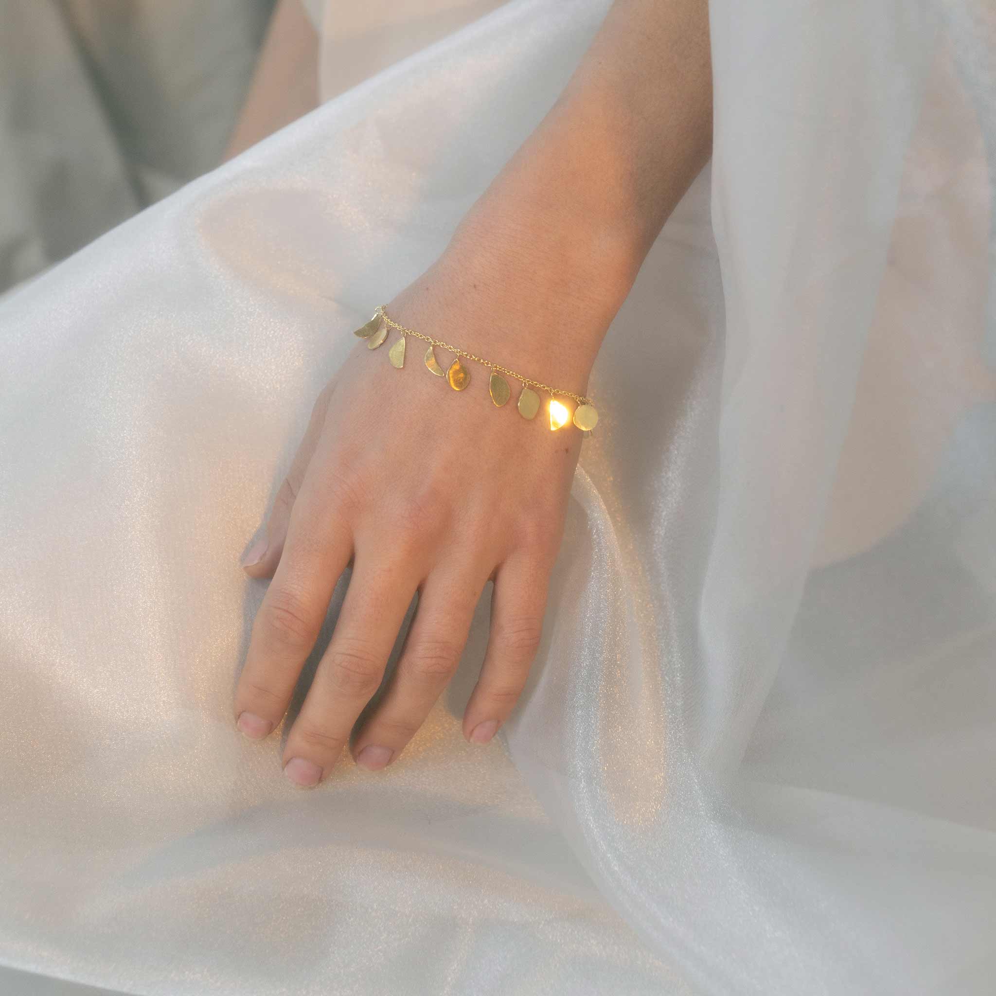 Lifestyle shot of ISHKAR's gold-plated sterling silver charm bracelet.