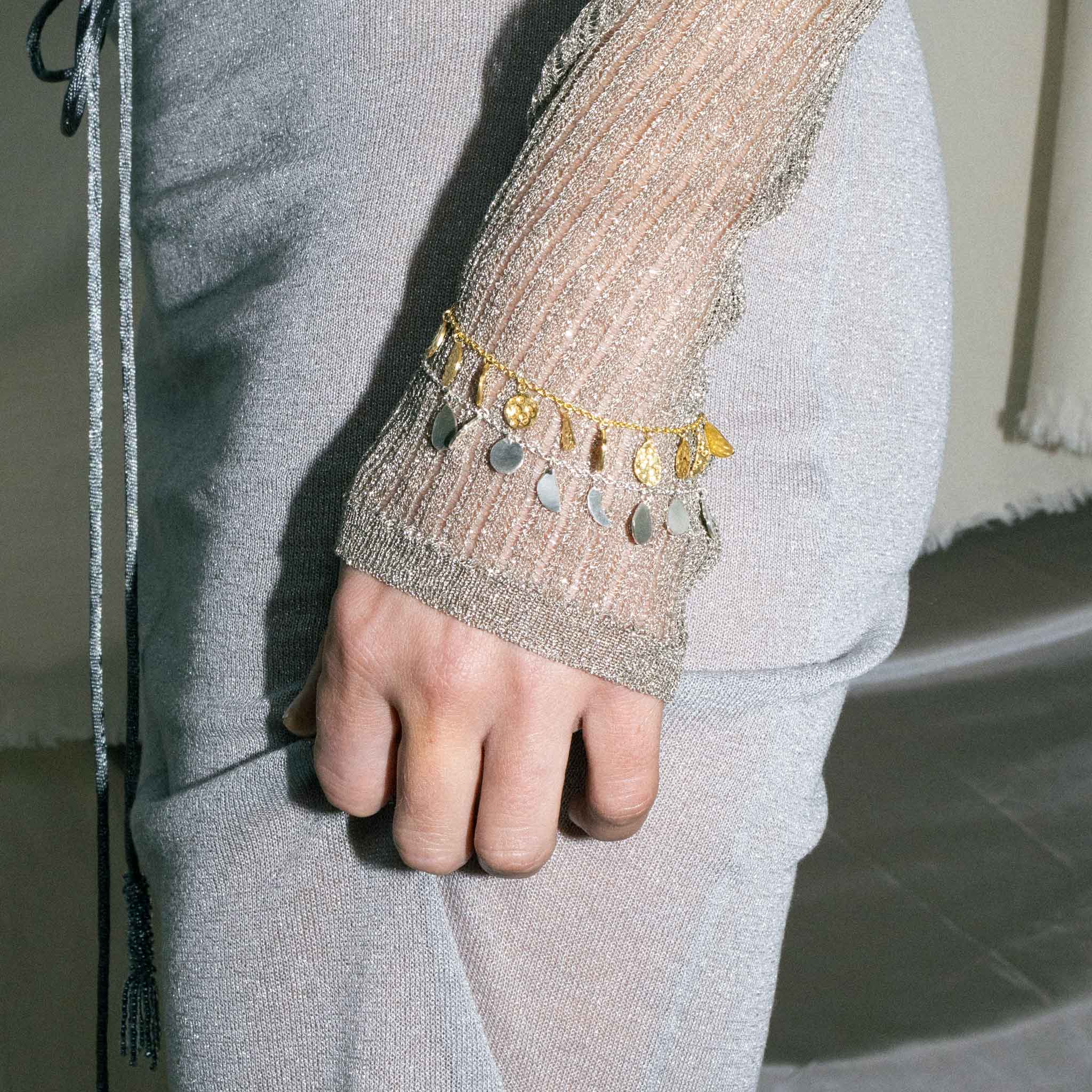 Lifestyle shot of ISHKAR's sterling silver and gold-plated sterling silver charm bracelets.