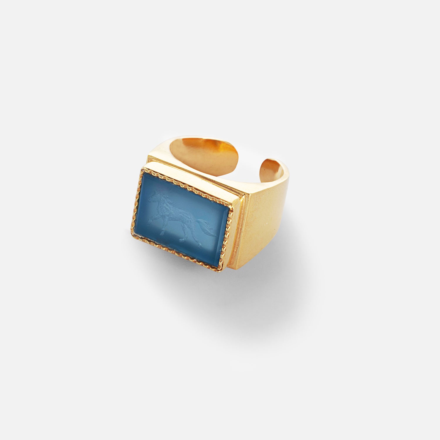 A blue agate ring with a silhouette of a galloping horse etched onto the stone, set in a gold-plated sterling silver band.