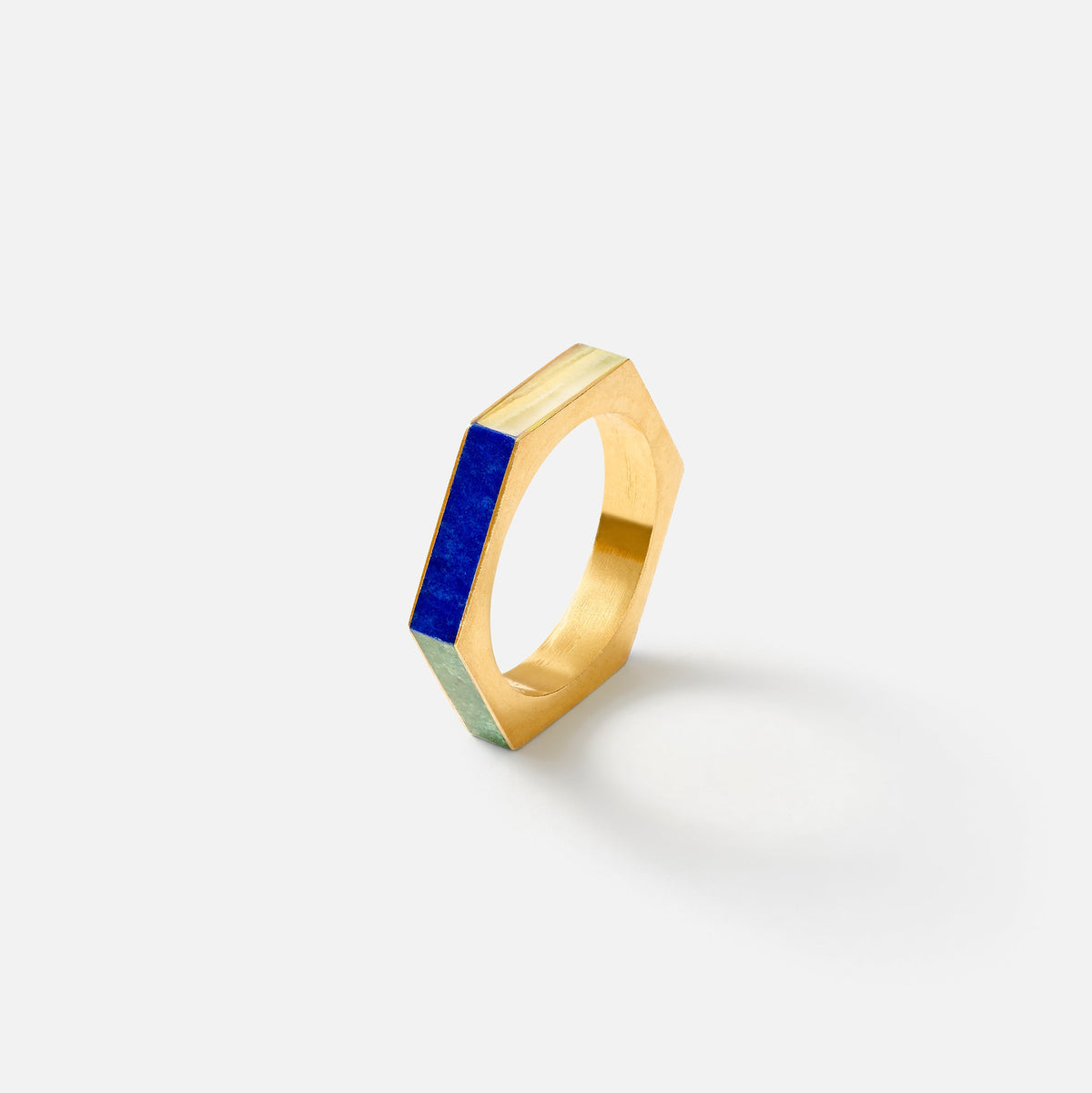 A gold hexagonal ring with a vibrant blue lapis lazuli crystal inlay, photographed on a clean white background with a soft shadow.