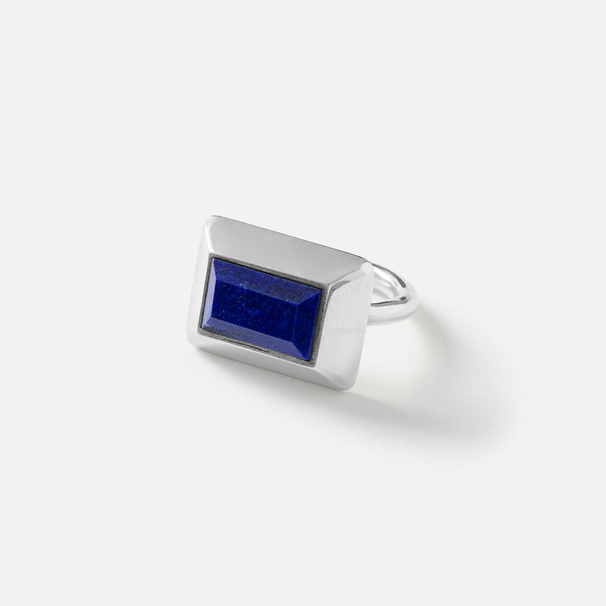 A silver-toned rectangular ring featuring a deep blue lapis lazuli stone, photographed on a clean white background with a soft shadow.