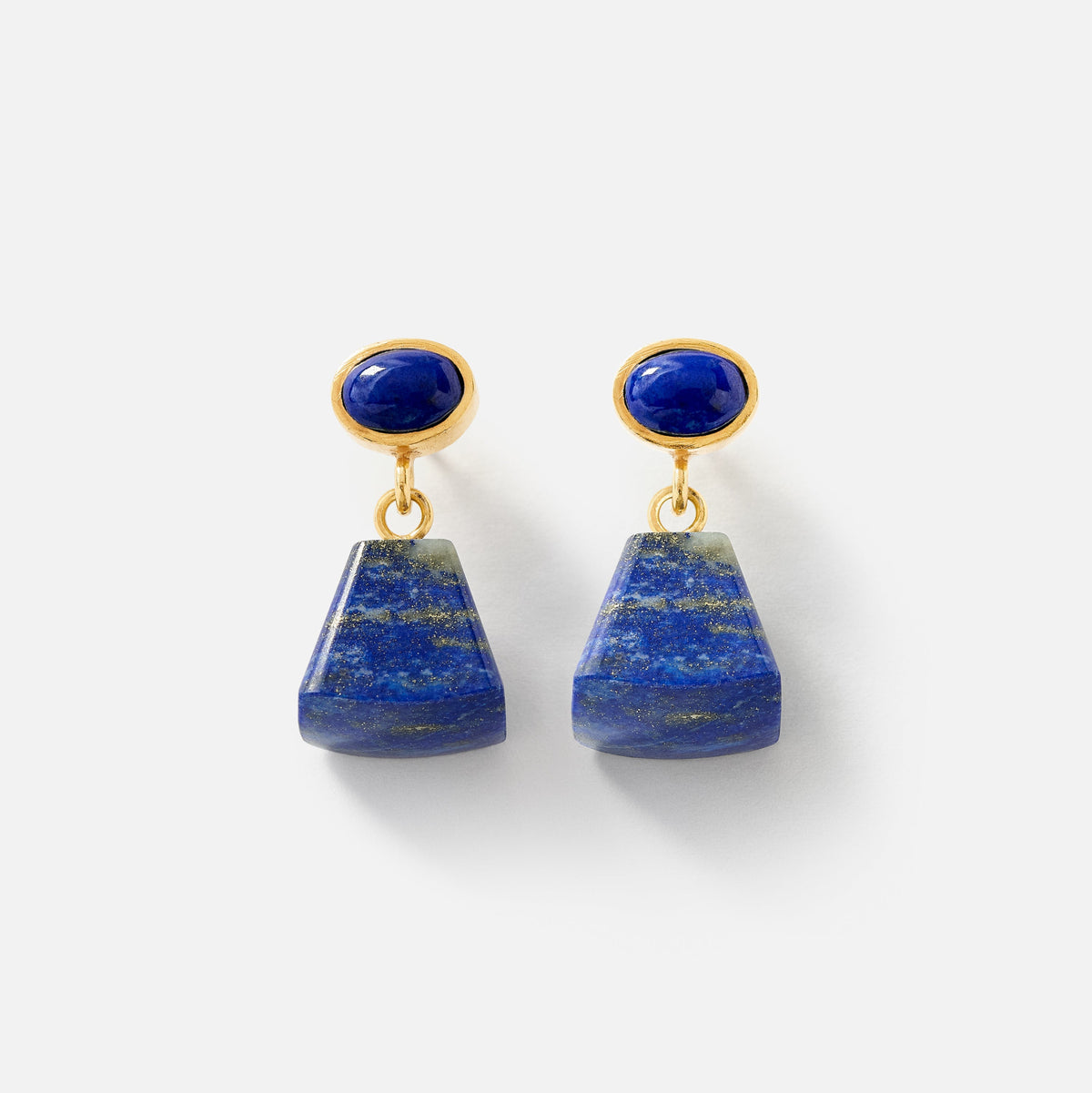 A pair of gold drop earrings featuring oval blue lapis lazuli stones at the top and larger, tapered blue lapis lazuli pendants below, shown on a light gray background.