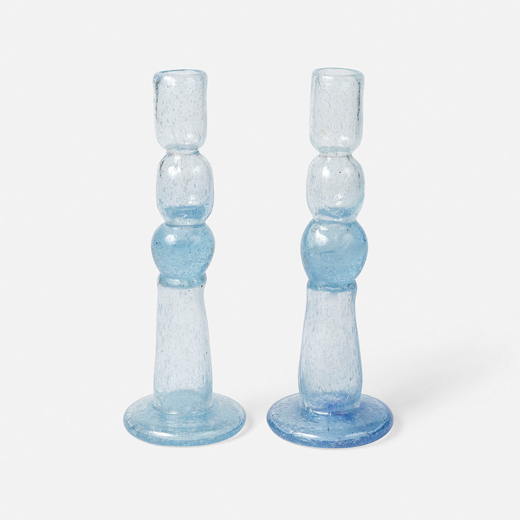 Two clear handblown glass candle holders on a white background