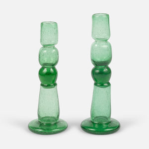 Two green glass candle holders on a white background