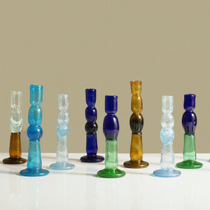 Set of colorful glass candle holders on a neutral background