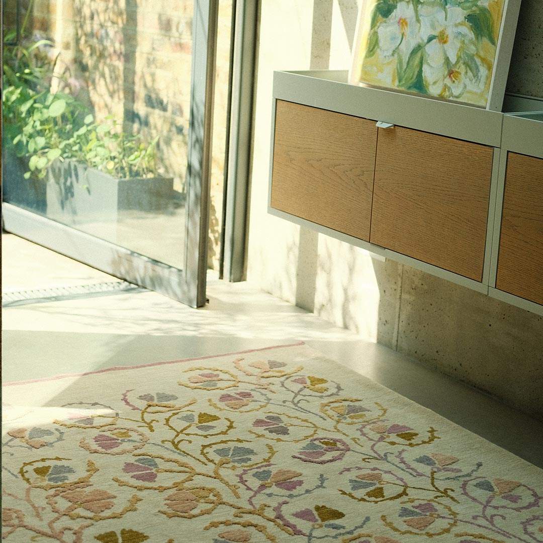 Decorative hand-knotted rug with floral pattern in a room with wooden cabinets and a painting.