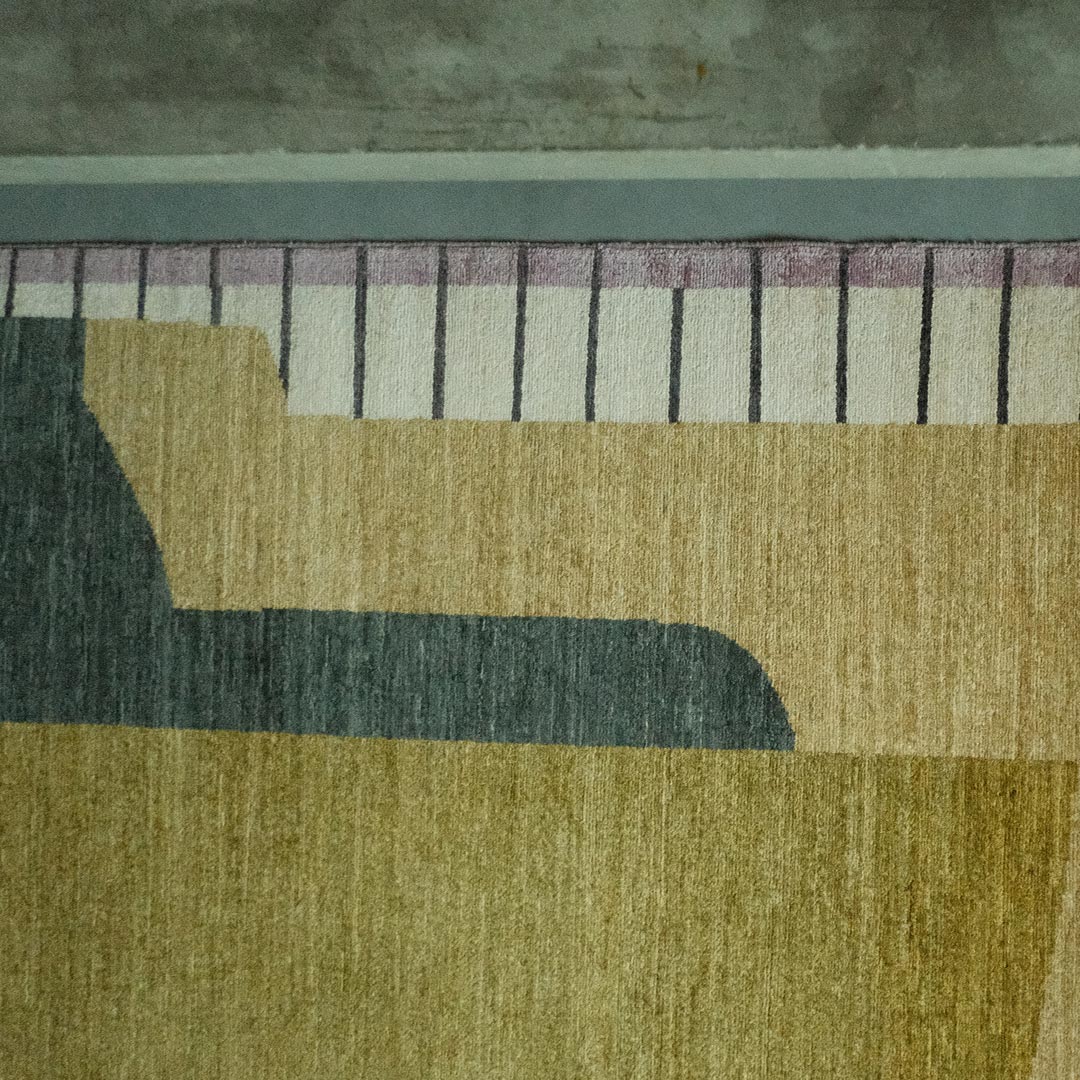 Close-up of hand-knotted wool rug with abstract design against concrete floor