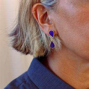 Close-up of a person wearing Chasma gold-plated drop earrings with lapis lazuli.