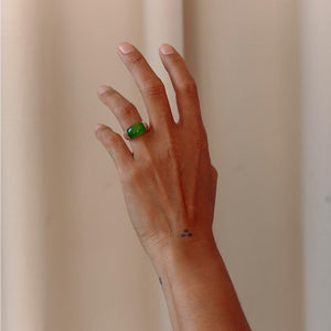 Hand with a sterling silver ring with green agate on a plain background