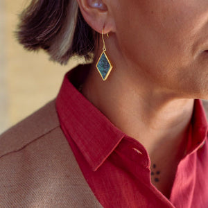 Close-up of a person wearing a gold-plated earrings with a Bamiyan turquoise.