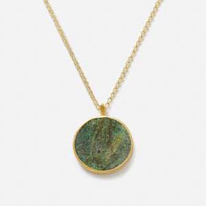 A pendant necklace with a large circular disc featuring a green stone, Bamiyan Turquoise.