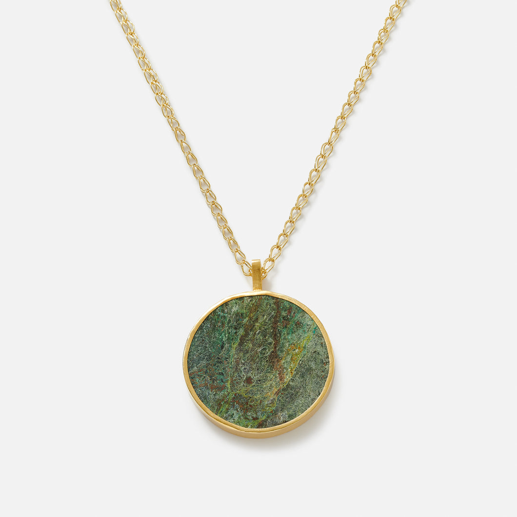 A pendant necklace with a large circular disc featuring a green stone, Bamiyan Turquoise.