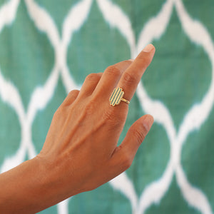 A gold-plated sterling silver ring with Bamiyan Turquoise, inspired by the view of Afghanistan’s verdant fields, against an ikat fabric.