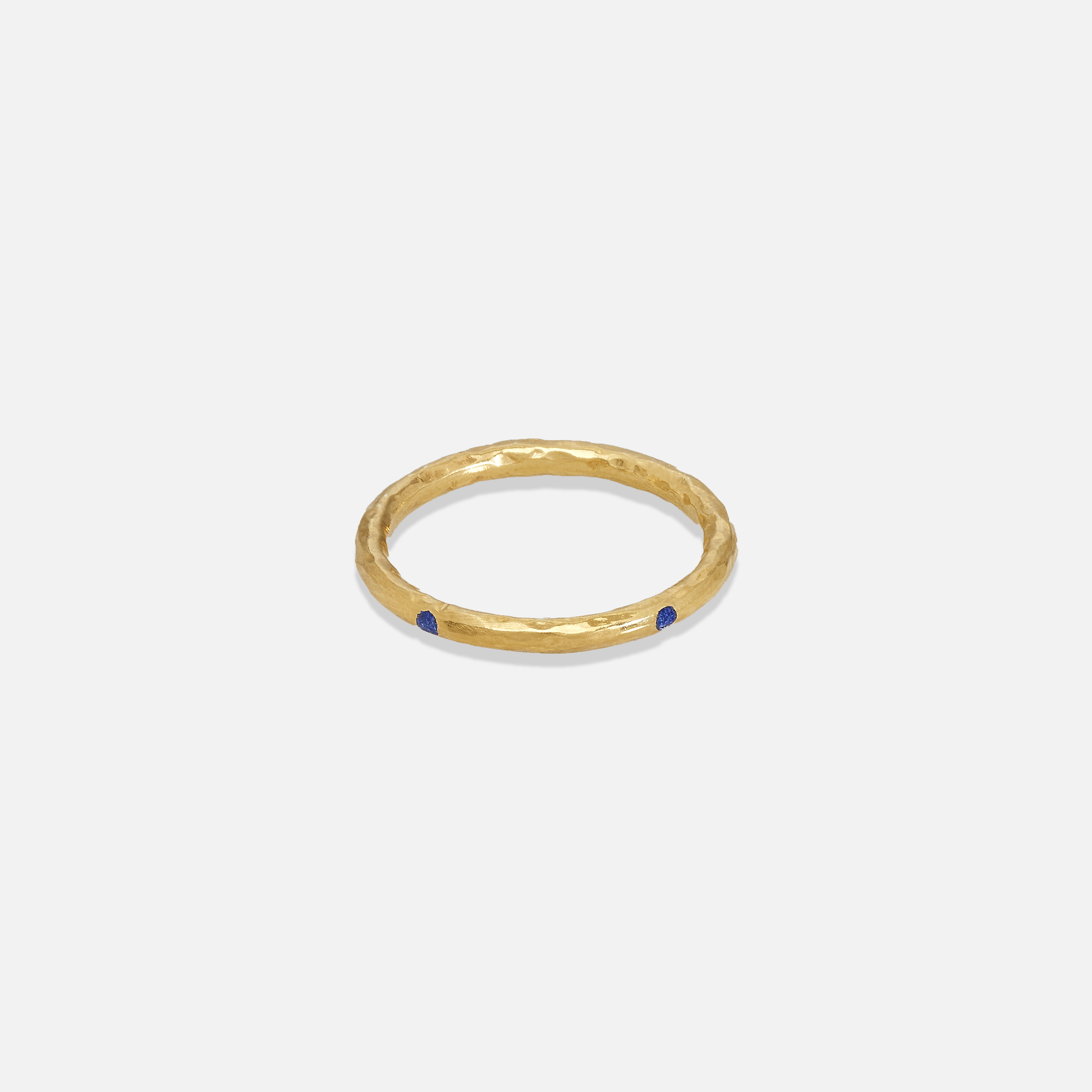 A gold colored band ring with lapis inlays on a white background.