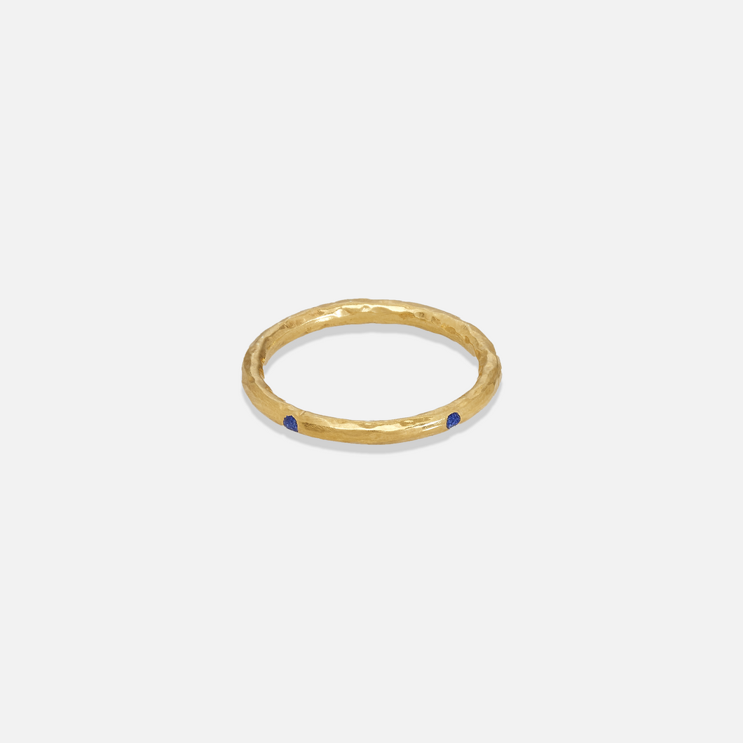 A gold colored band ring with lapis inlays on a white background.