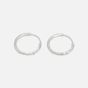 A pair of silver hoop earrings with lapis accents on a white background.