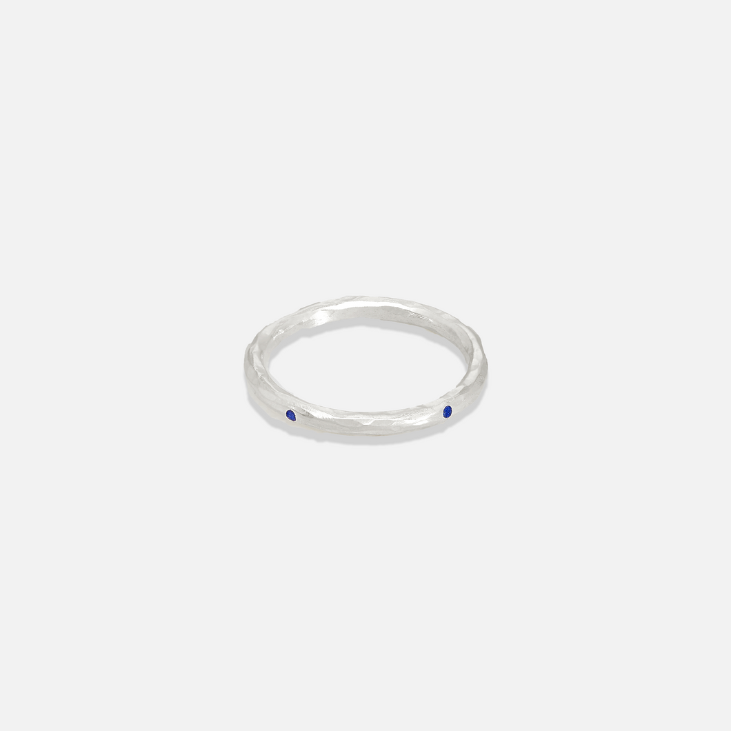 A simple silver band ring with two small blue stones on the top surface.