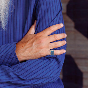 Man wearing a filigree sterling silver ring with a blue agate stone depicting a silhouette of a galloping horse.