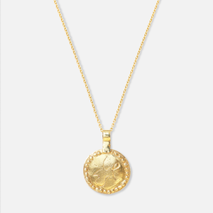 Back side of the gold-plated necklace with a circular pendant featuring a snow leopard and an emerald on one side, and the word "Peace" in Dari on this side.