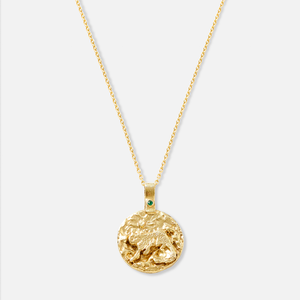 A gold-plated necklace with a circular pendant featuring a snow leopard and an emerald.