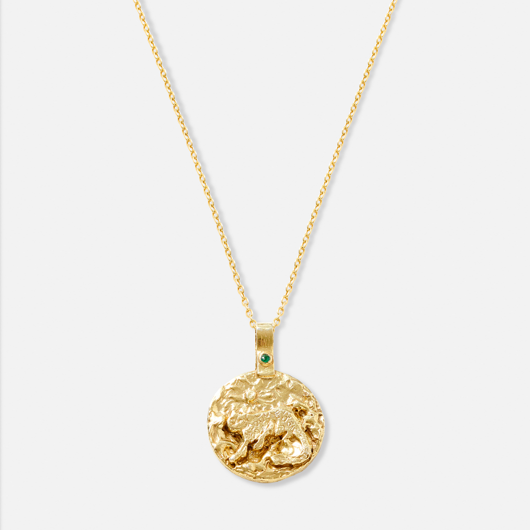 A gold-plated necklace with a circular pendant featuring a snow leopard and an emerald.