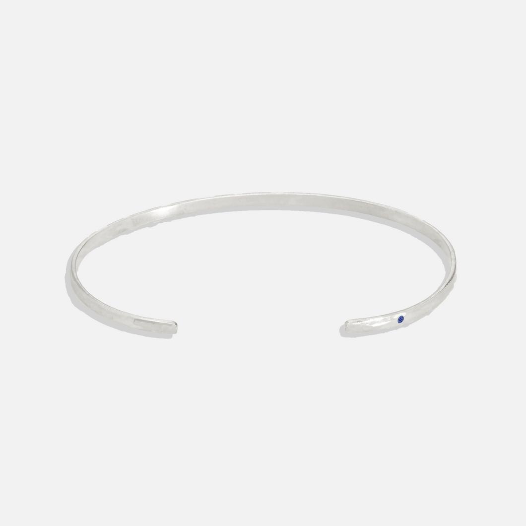 ISHKAR classic oval silver bangle with a small blue gemstone on one end.