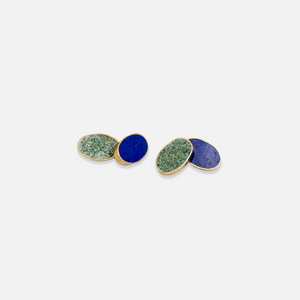 A pair of cufflinks with one half featuring a blue stone inlaid in silver and the other half featuring a green stone inlaid in silver, set against a white background.